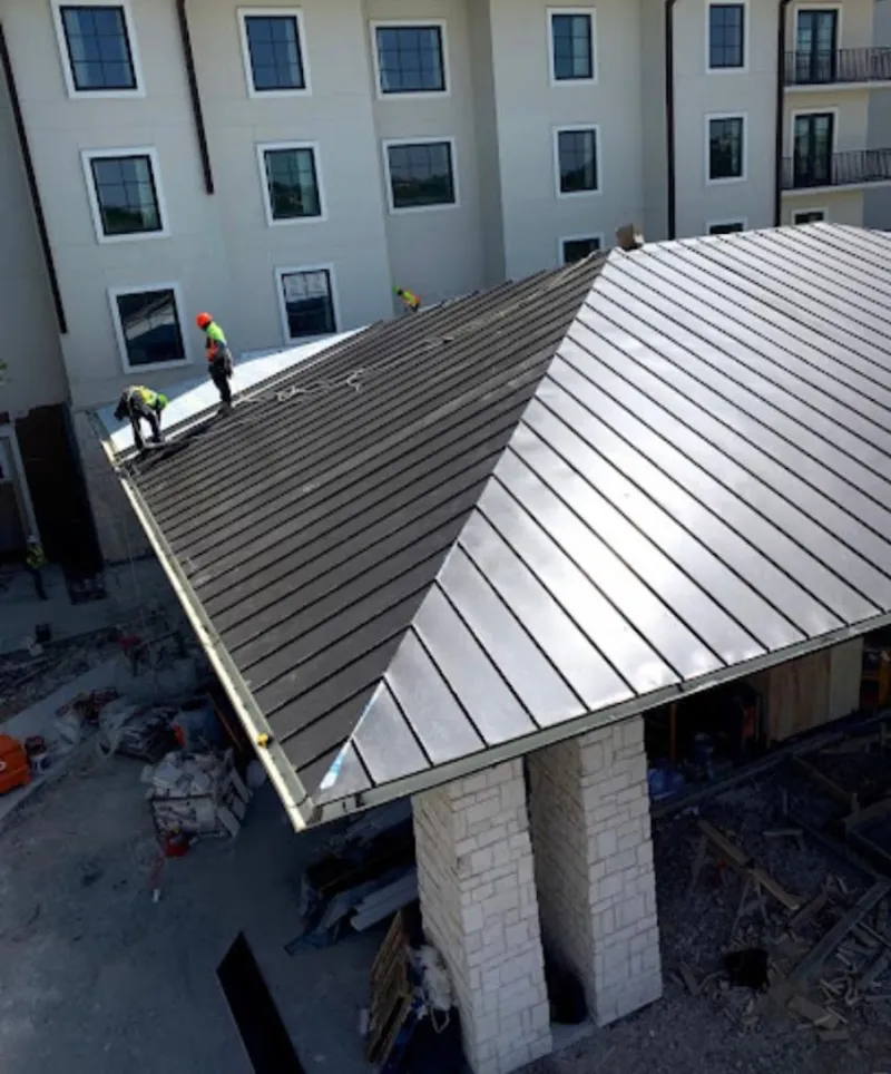 Crew installing standing seam metal roof panels on a commercial project in Princeton